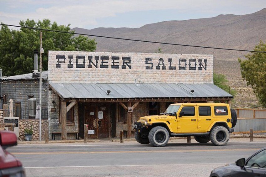 A yellow Jeep parked in front of a building with a sign reading 'Pioneer Saloon.' 5