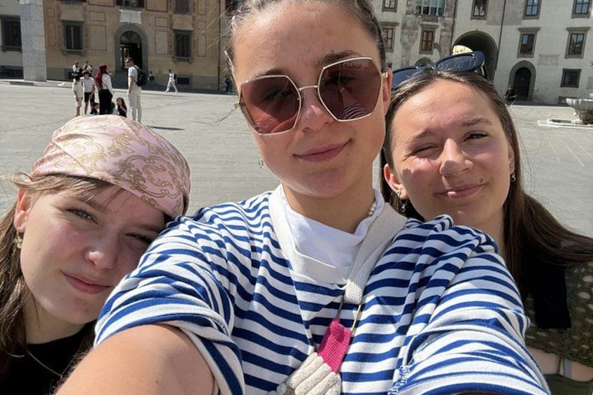 Three people taking a selfie in a public square with historical buildings in the background. 2