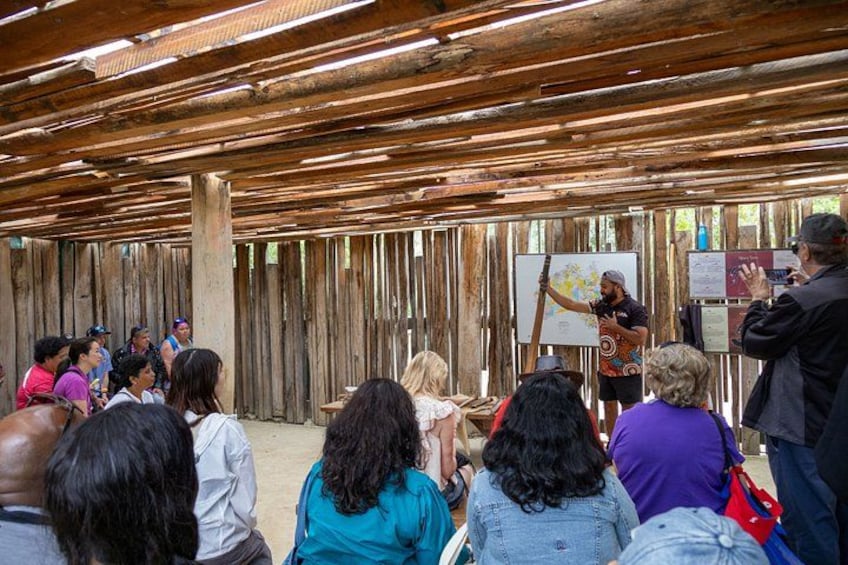 A group of people seated indoors, facing a person presenting at a whiteboard. 2