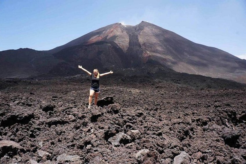 Una persona de pie sobre terreno rocoso, con un volcán al fondo. 3