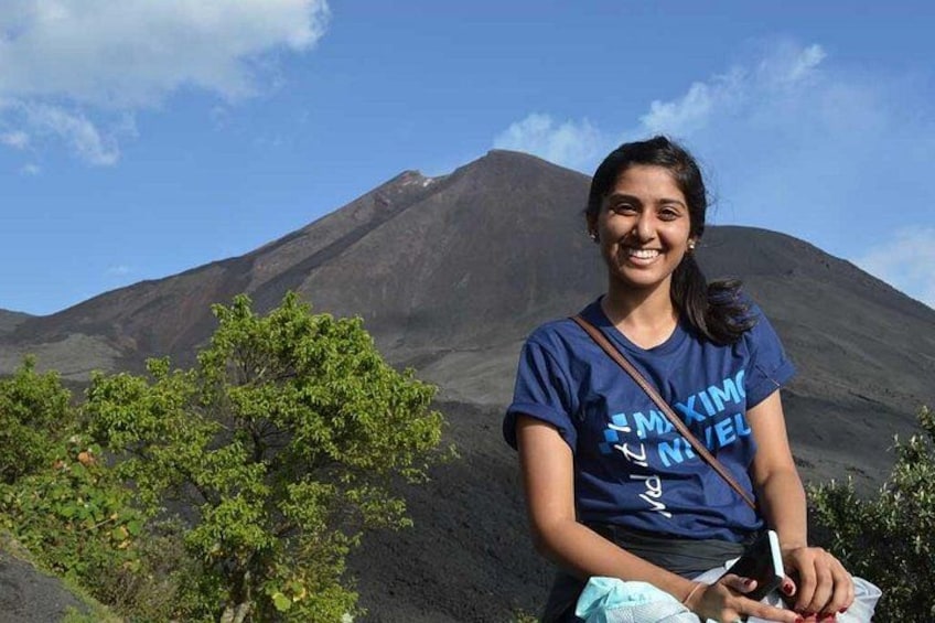 Una persona de pie frente a un volcán con cielo despejado. 2