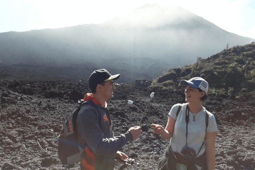 Dos personas caminando por terreno volcánico, con una montaña al fondo. 5
