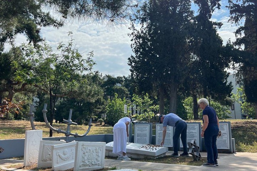 People at a cemetery with headstones and memorial plaques. 1