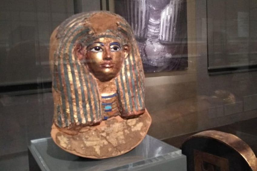 An ancient Egyptian sarcophagus with hieroglyphics and a figure wearing a striped headdress. 5