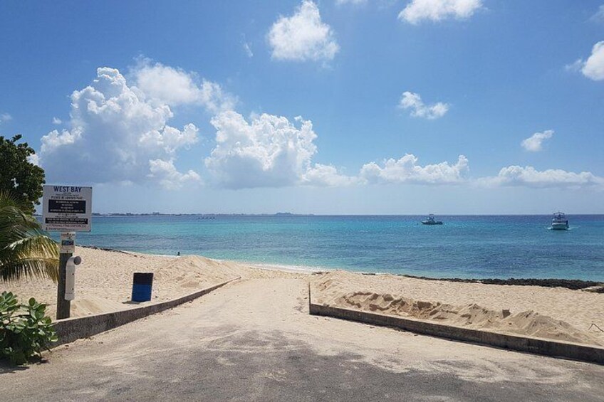 En strand med en skylt som visar att det är ”West Bay”, och en klar, blå himmel. 3