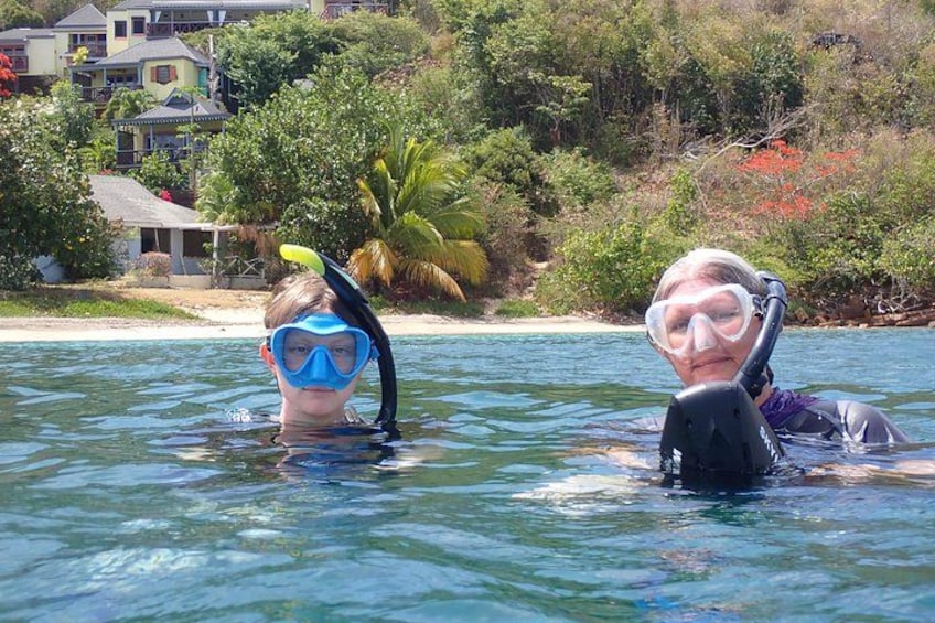 Zwei Personen, die in einem Pool schnorcheln, mit tropischer Landschaft im Hintergrund. 2