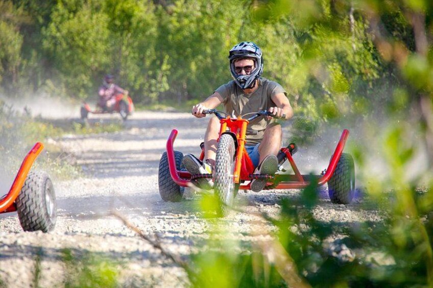 En person cykler på en støvet sti, mens en anden cykel ses i baggrunden. 3