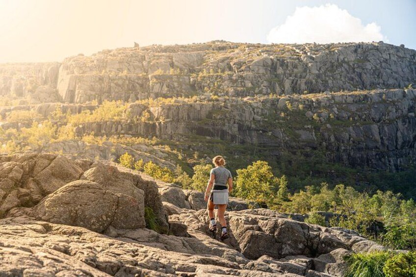 Eine Person wandert über felsiges Gelände, im Hintergrund eine gebirgige Landschaft. 3