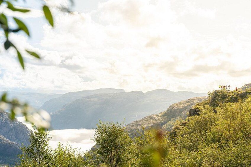 Eine gebirgige Landschaft mit einem Tal und einer Gruppe von Personen auf einem Grat. 4
