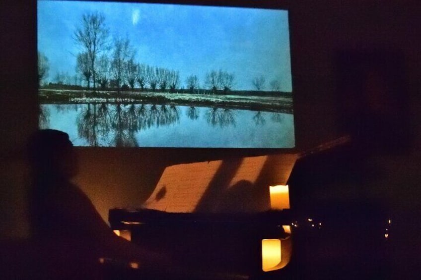 A projection of a landscape with trees and a body of water, a chair, and a lit candle. 4