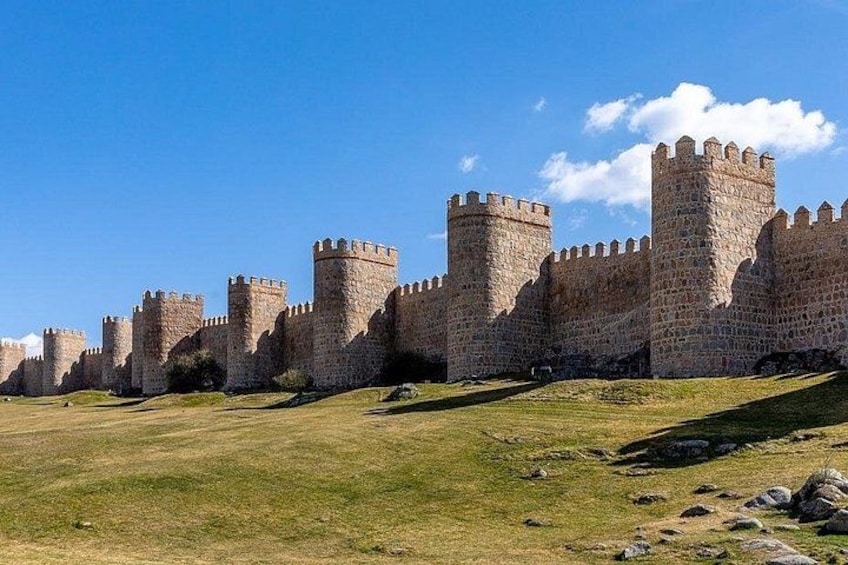 Un château médiéval en pierre, doté de nombreuses tours et précédé d’une pelouse verdoyante. 3