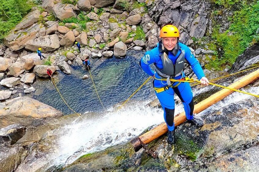A person in blue gear rappelling down a rocky riverbank. 2