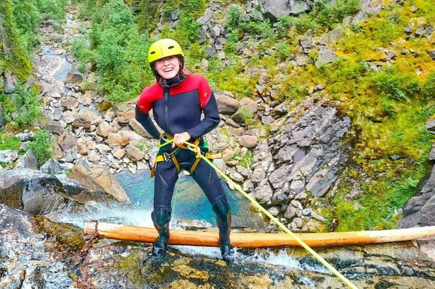 A person in a wetsuit and helmet standing on a raft in a rocky river. 3