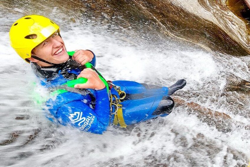 Une personne vêtue d’une tenue de sport nautique bleue et d’un casque jaune navigue sur un cours d’eau à rapides. 1