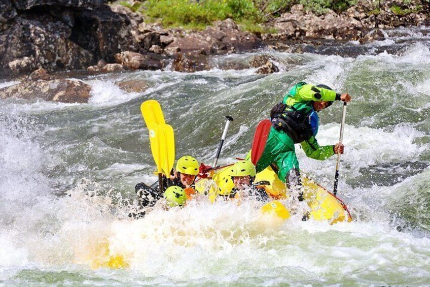 A person in a yellow raft navigating through white water rapids. 4