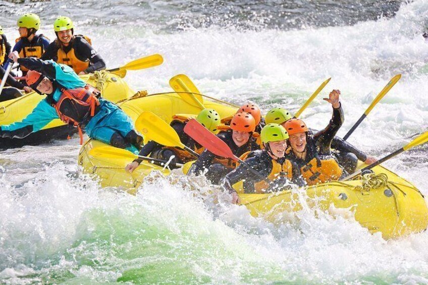 People in a yellow raft navigating through white water rapids. 3