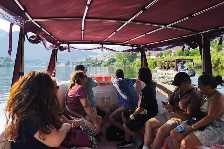 A group of people on a boat with a canopy, looking at a cooler and a map. 4