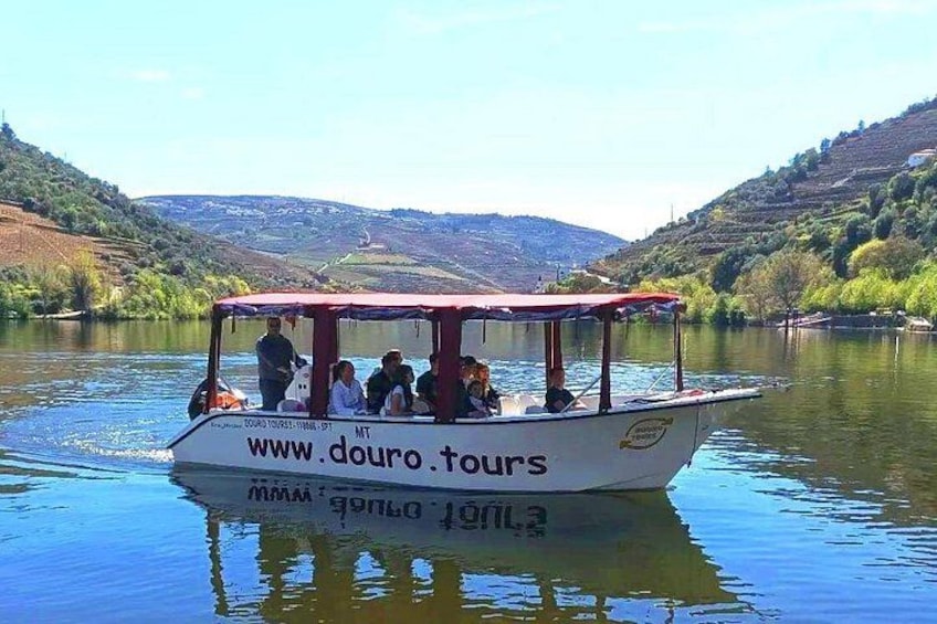 A boat with people on it, surrounded by a calm river and hilly landscape. 3