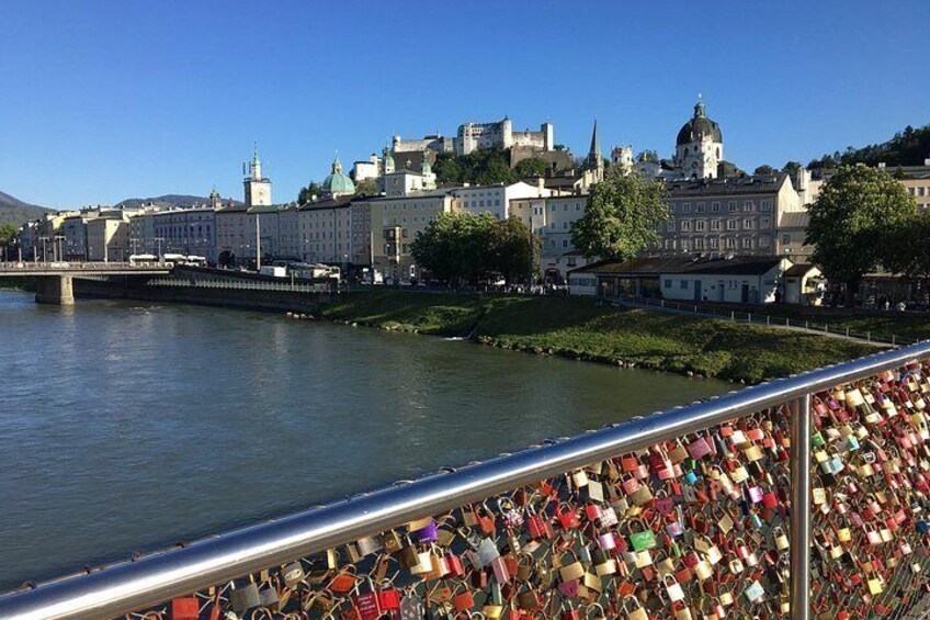 A river with a bridge, a cityscape with historic buildings, and a fence with padlocks. 4