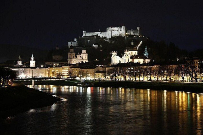 A castle on a hill overlooking a river at night. 5