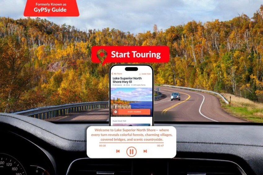 A smartphone displaying a map on a dashboard with a scenic view of a winding road and autumn foliage. 1