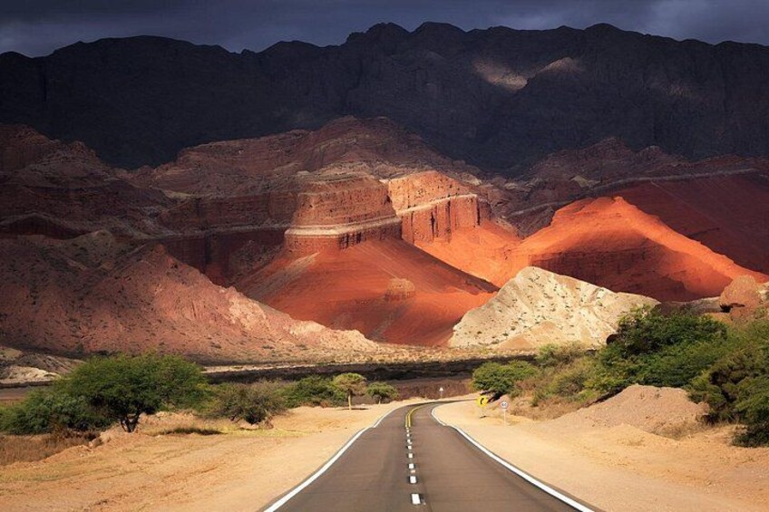 A road winding through a canyon with red rock formations and sparse vegetation. 4