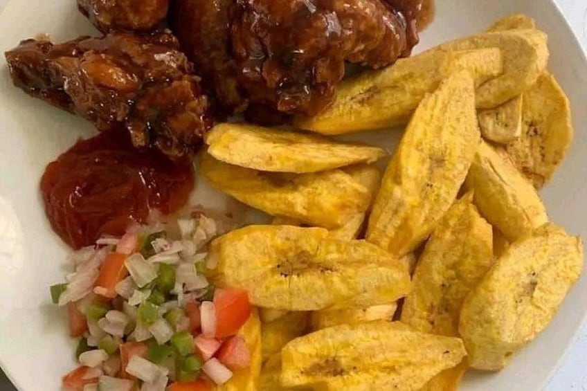 Une assiette de nourriture comprenant de la viande, des bananes plantains frites et une sauce salsa. 4