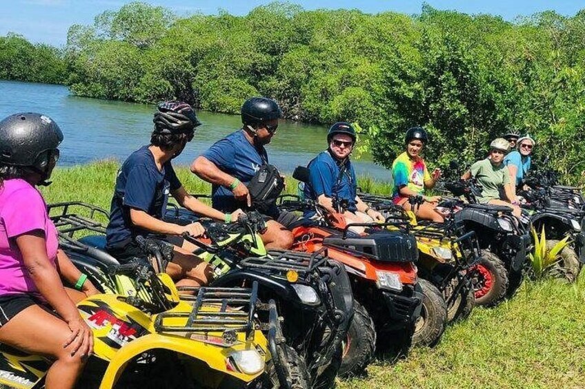 Un groupe de personnes conduisant des quads près d’une rivière. 5