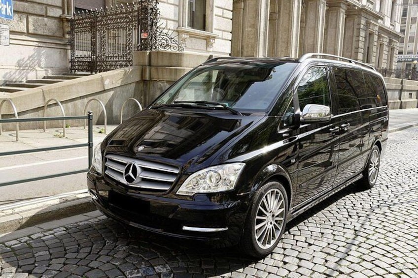 A black Mercedes-Benz minivan parked on a cobblestone street. 2