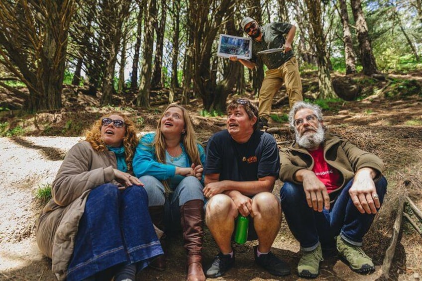 Un grupo de personas sentadas en un sendero de tierra en un bosque. 3