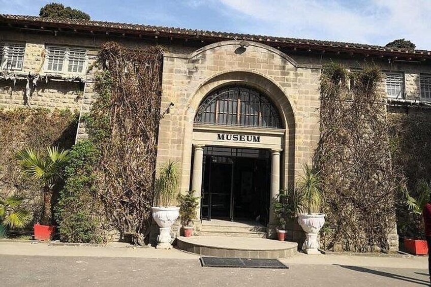 Un bâtiment en pierre avec une enseigne indiquant « MUSÉE » et une grande entrée en arc de cercle. 1