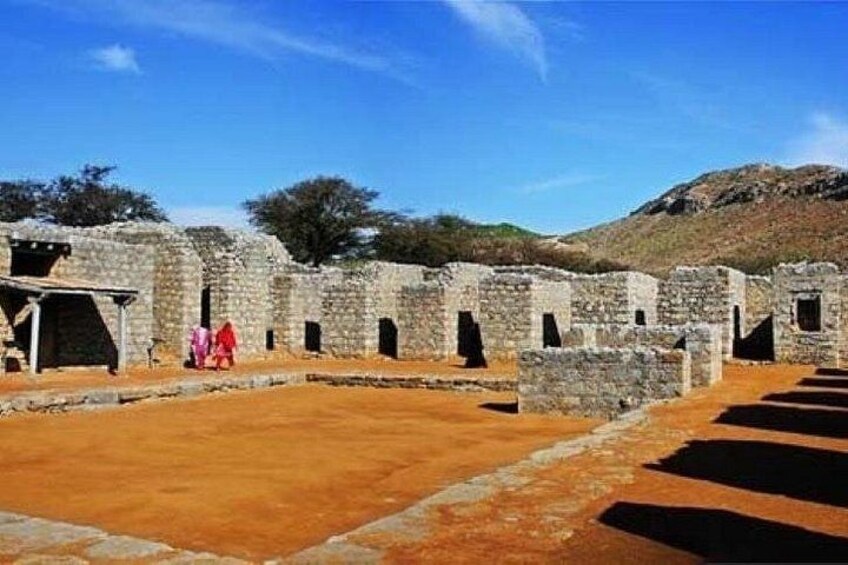 Vestiges d’anciens bâtiments en pierre, avec des portes en arc de cercle, sous un ciel dégagé. 5
