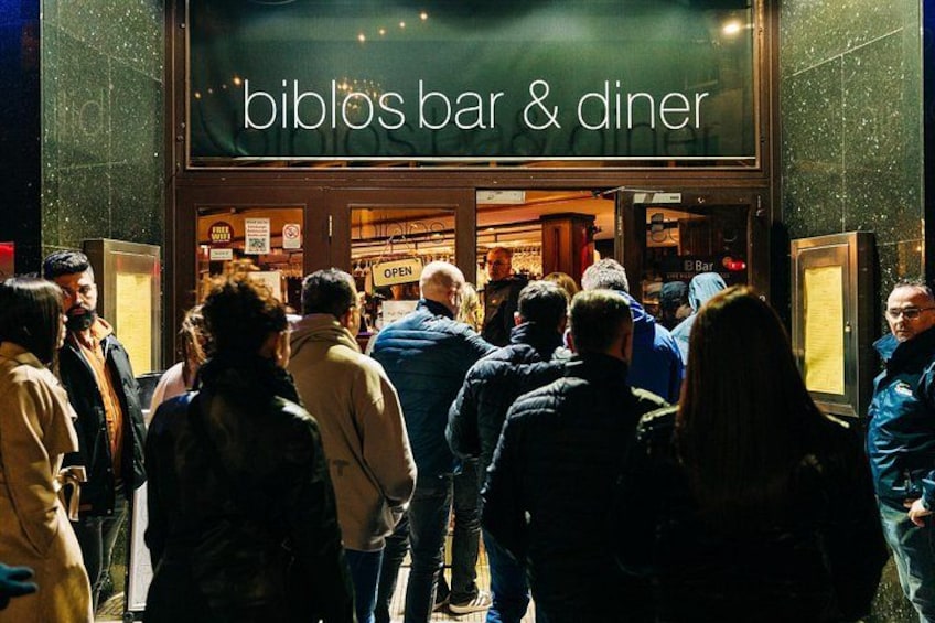 A crowd outside a bar and diner named 'biblos bar & diner'. 2