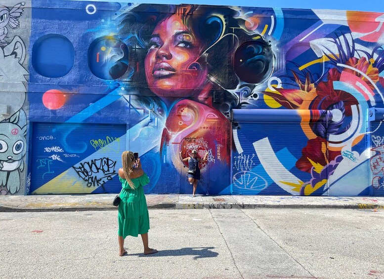 A colorful mural on a building with a woman taking a photo. 2