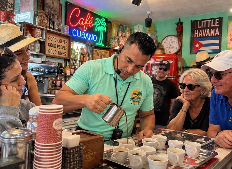 A barista preparing coffee in a cafe with a neon sign and Cuban flag decorations. 4