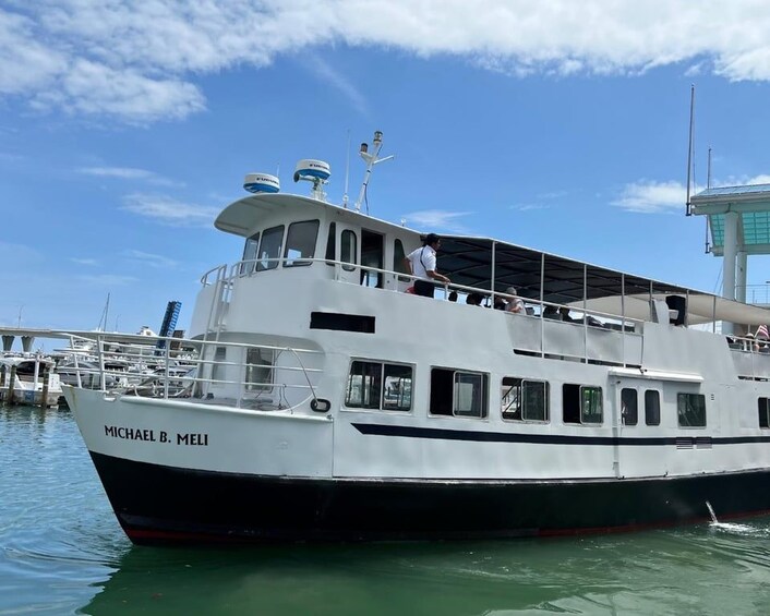 A white and black boat named 'MICHAEL B. MELI' docked at a marina with a clear sky and calm water. 3