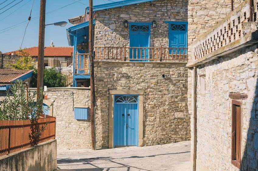 A stone building with blue doors and shutters, a balcony, and a clear sky. 2