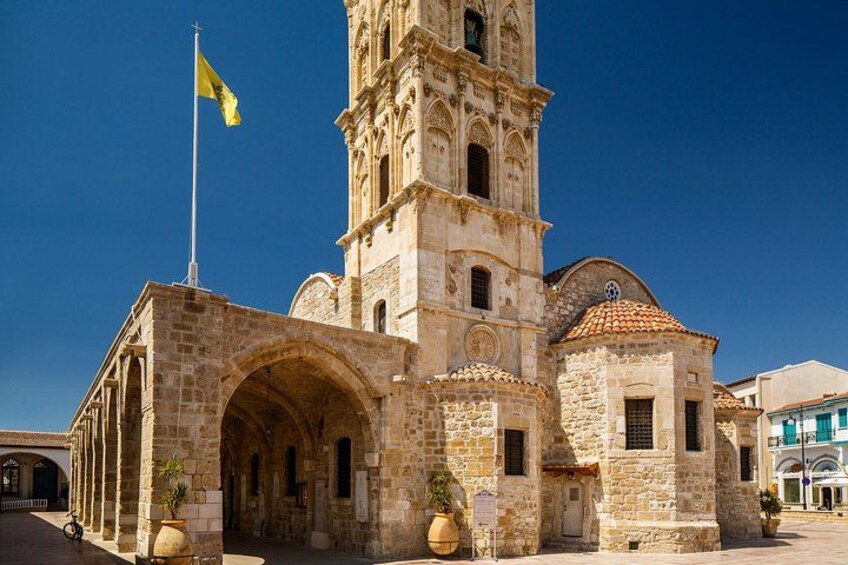 A historic stone building with a bell tower, arched entrance, and a flag. 4
