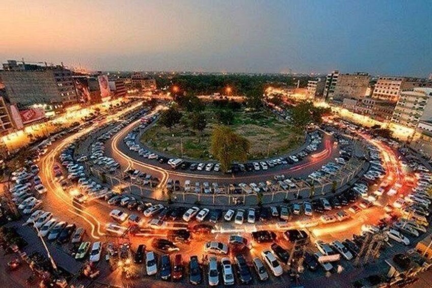 A circular road with multiple lanes and a central roundabout surrounded by parked cars. 2