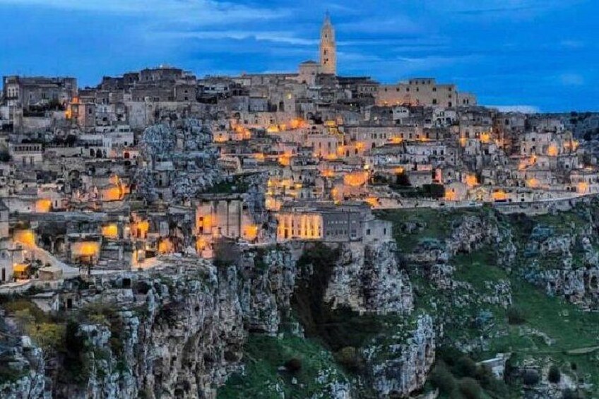 A historic town with stone buildings, a prominent tower, and rocky terrain. 1