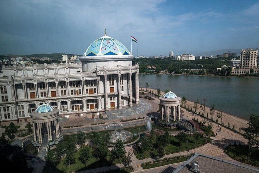 A large building with a dome and a flag, surrounded by a landscaped area with a body of water. 2