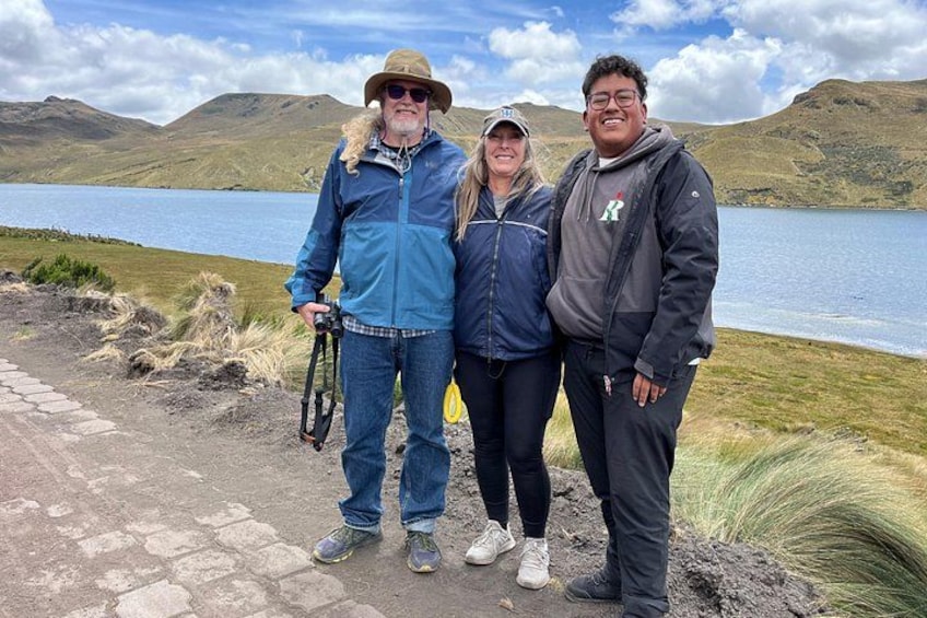 Trois personnes se tiennent près d’un lac, avec des montagnes en arrière-plan. 2