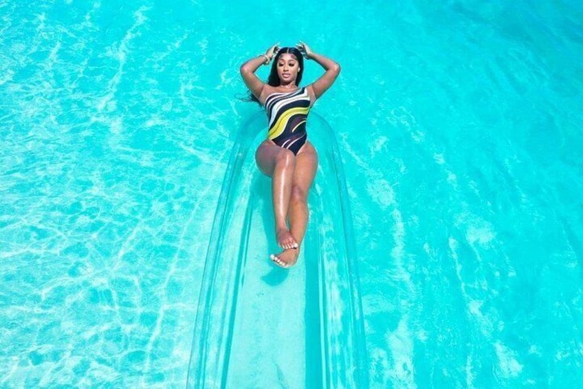 A person lying on a transparent tube in a pool. 5