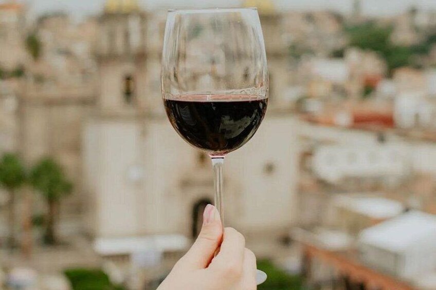A hand holding a wine glass with a view of a historic building in the background. 1