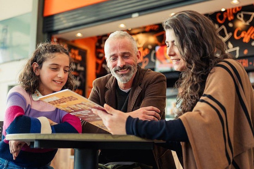 Three people sitting at a table in a cafe with a menu. 4