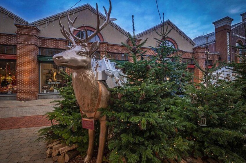 A large deer statue in front of a building with brick architecture and a Christmas tree nearby. 4