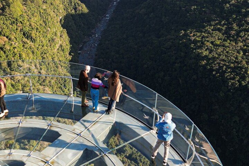 Un mirador de cristal con gente observando un valle. 5