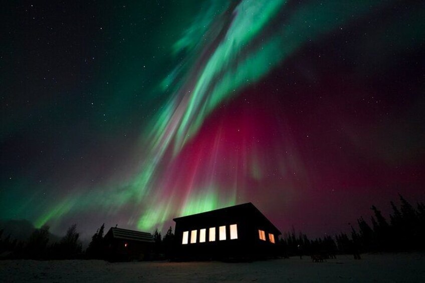 Una casa bajo un cielo nocturno con auroras boreales. 1