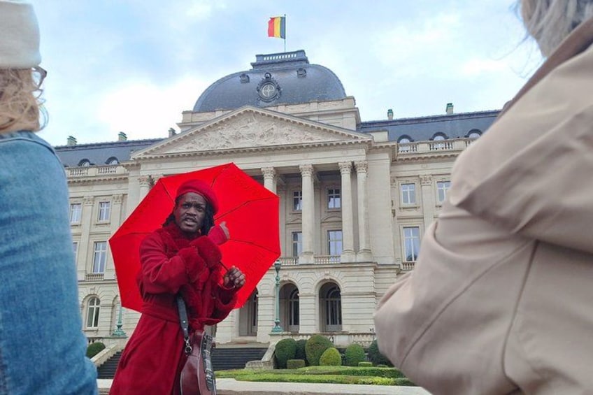 Une personne vêtue d’un manteau rouge, tenant un parapluie rouge devant un grand bâtiment orné de colonnes et surmonté d’un dôme. 4