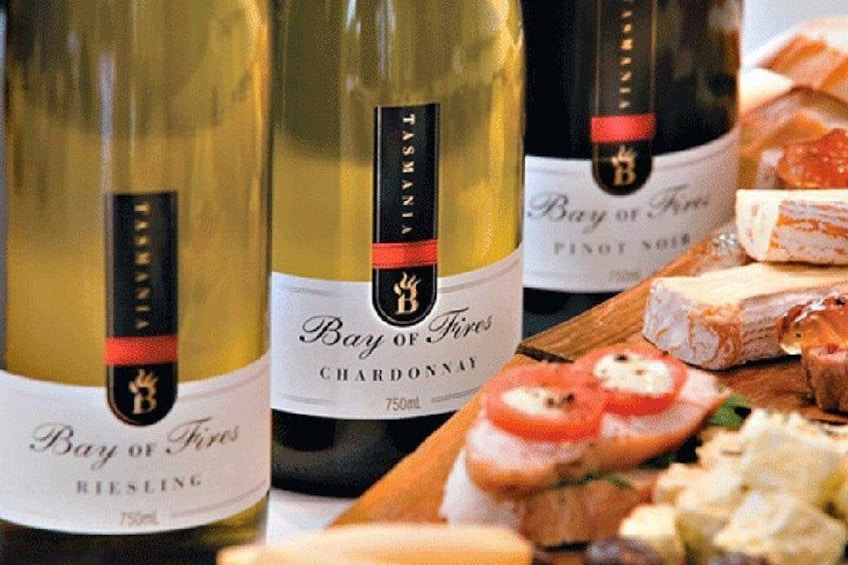 Flaschen Bay of Fires Chardonnay und Pinot Noir, sowie ein Holzbbrett mit Käse und Tomatenscheiben. 2